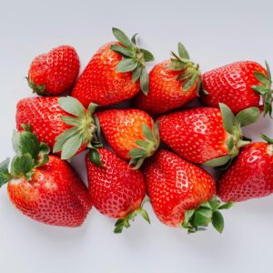 Top view of vibrant fresh strawberries arranged neatly on a white backdrop.
